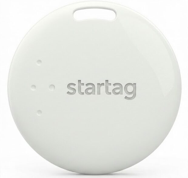 A round, white electronic tag with the word startag embossed in the center. The tag has a small slot at the top and three small dots on the left side. The background is plain white with black borders.