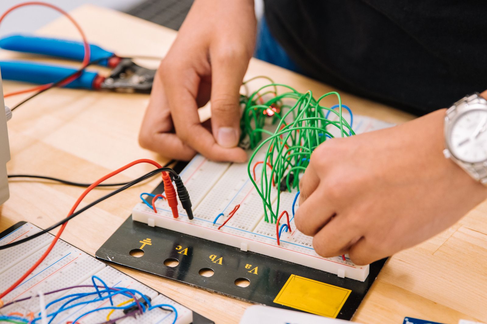 Hands testing a generic electronic circuit on a breadboard with measurement leads